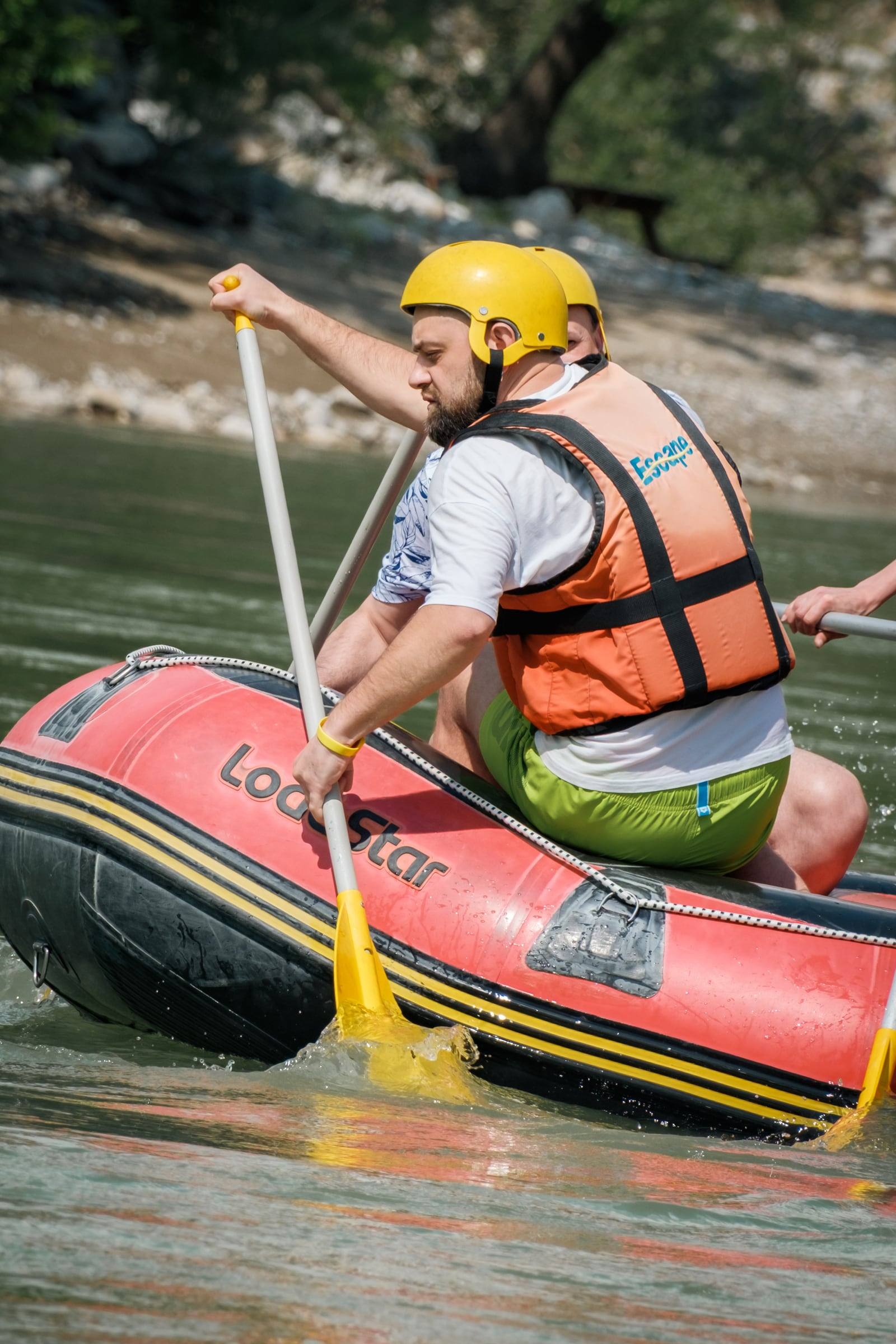 Man paddling a red raft on the river