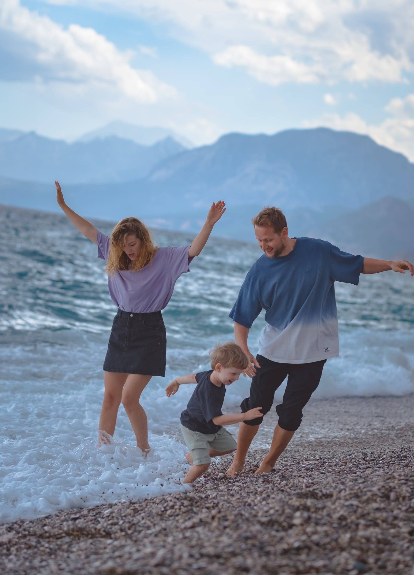 Family splashing in the waves with mountains behind